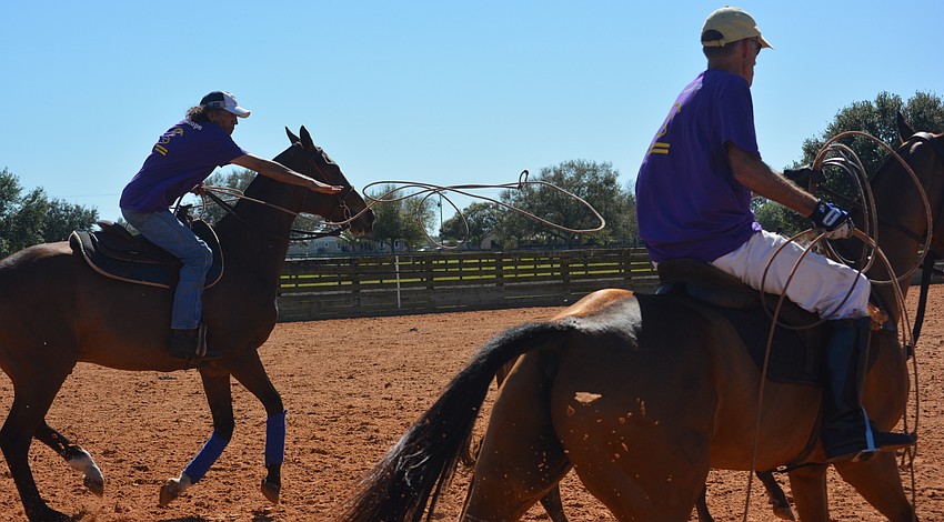 Lucio Amerigo Gomez, representing the polo players, releases his lariat as Dixon Stroud watches.