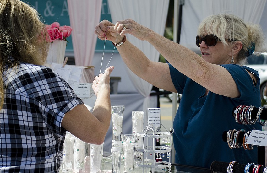 Lori Green shows a customer a necklace at the 23rd annual Siesta Key Craft Festival.