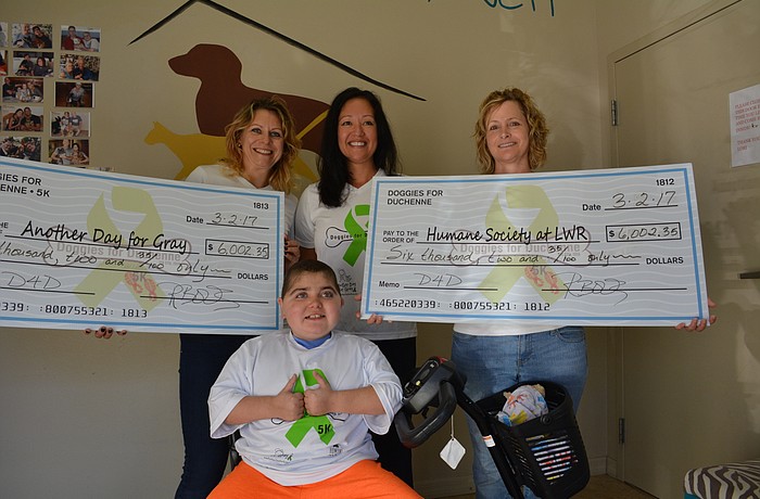 Doggies for Duchenne Race Directors Monika Oberer  and Rebekah Boudrie  present checks to Humane Society at Lakewood Ranch volunteer Becky Toter, right, and Another Day for Gray inspiration Grayson Tullio, front.