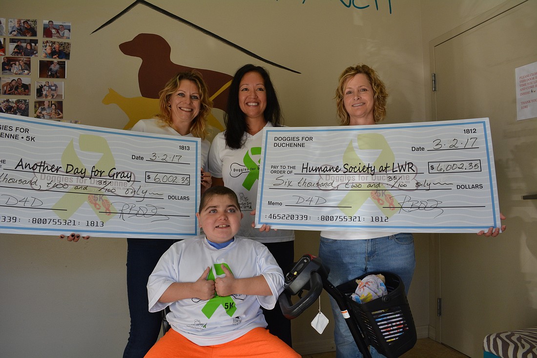 Doggies for Duchenne Race Directors Monika Oberer  and Rebekah Boudrie  present checks to Humane Society at Lakewood Ranch volunteer Becky Toter, right, and Another Day for Gray inspiration Grayson Tullio, front.