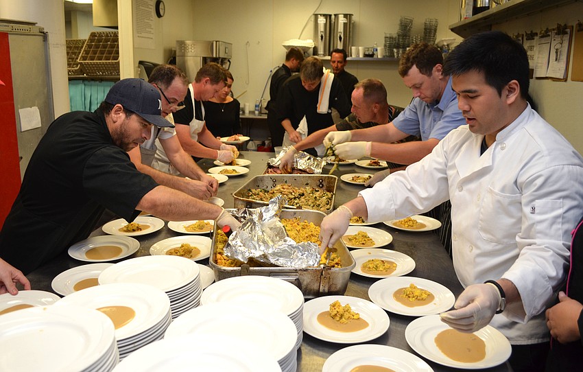 Chefs work with the Michael’s On East catering team to plate Christian Hershman’s fifth course dish of Memphis cured and lightly smoked pork shoulder steak at Foodlosophy on March 10 at Michael’s On East.