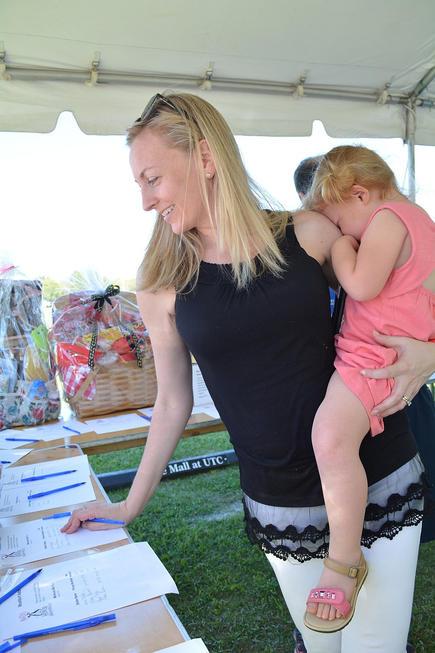 Heather Chadwick gets help from her daughter, Kinsley, 2, in picking out silent auction items.