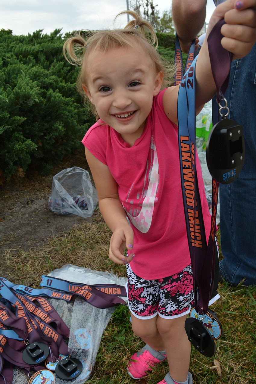 Jolene McHugh, 3, helps her mother and race organizer Leslie McHugh, prepare the finishers'    medals.