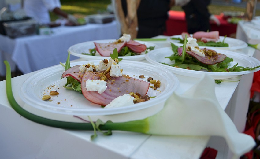Employees at the Fête Catering & Ballroom table at station #1 serve beet, goat-cheese and pistachio salad over arugula at the 5th annual Wine Walk to Ca’ d’Zan on March 31 at The Ringling.