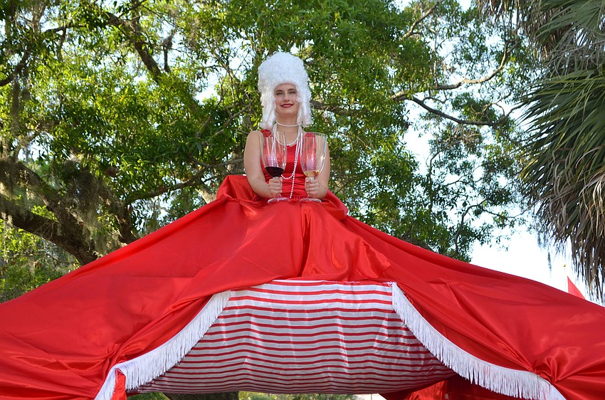 A costumed Red or White? woman smiles as guests pass under her and her dress, which serve as the entrance to the 5th annual Wine Walk to Ca’ d’Zan on March 31 at The Ringling.