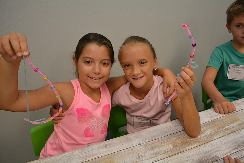 Leah Hegemier, of Braden River Elementary, and Addison Shear, of McNeal Elementary, show off their bead-and-string creations.