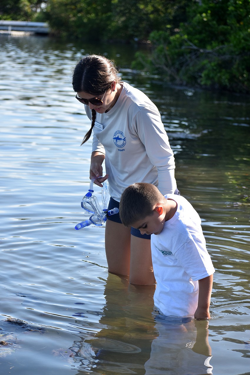 Mote Science Educator Kiley Gray and Mason Dennis wade into the water.