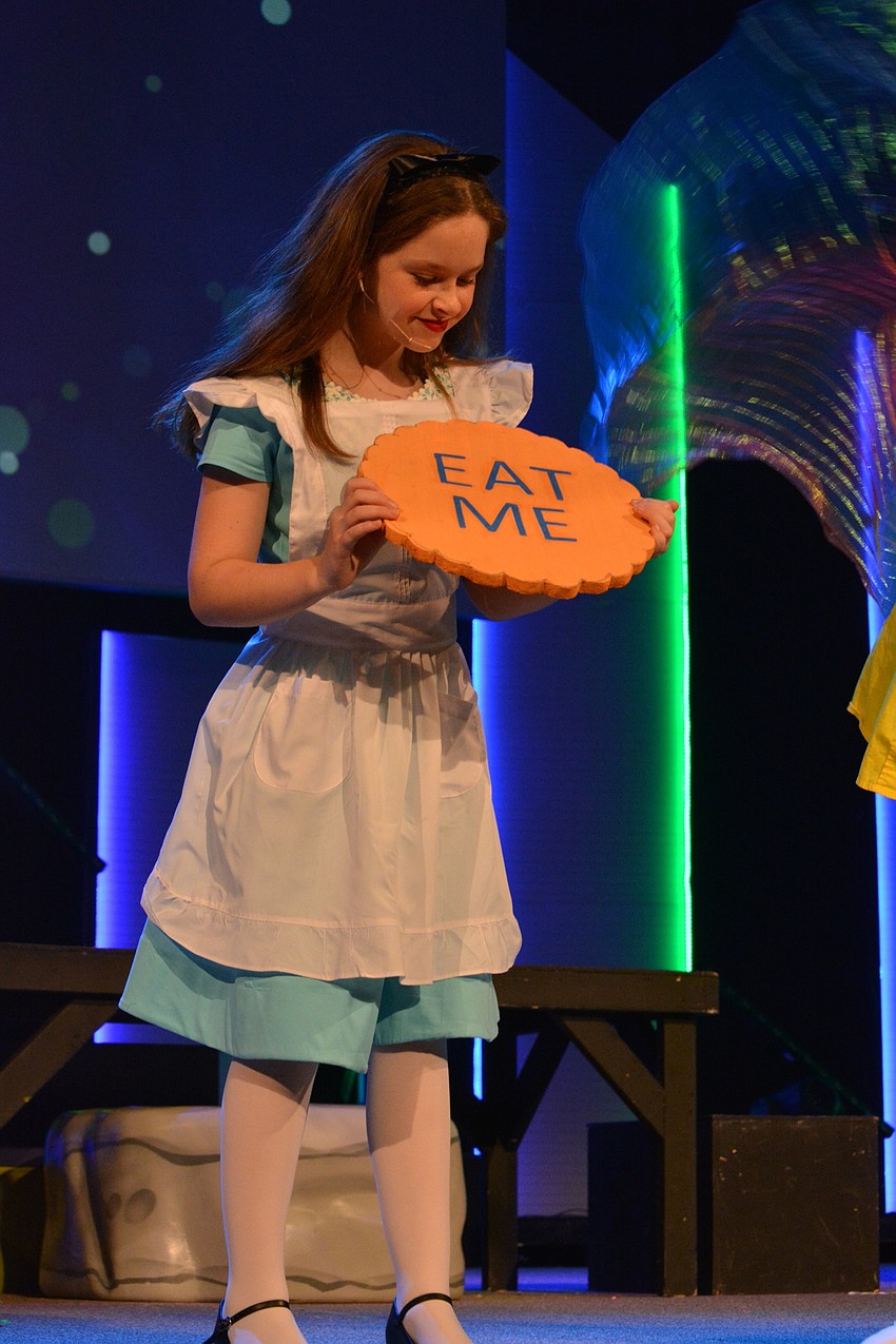 Alice, played by Sophia Clauson, laments about being only 3 inches tall and eats a cookie to regain a more normal size.