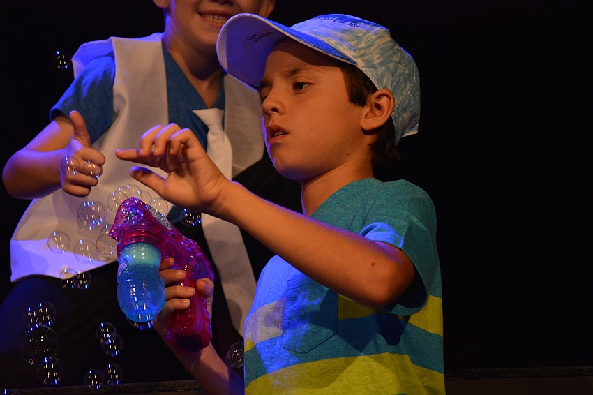 Michael Sandwall, with Chance Horvath behind, blows bubbles during a playground scene.