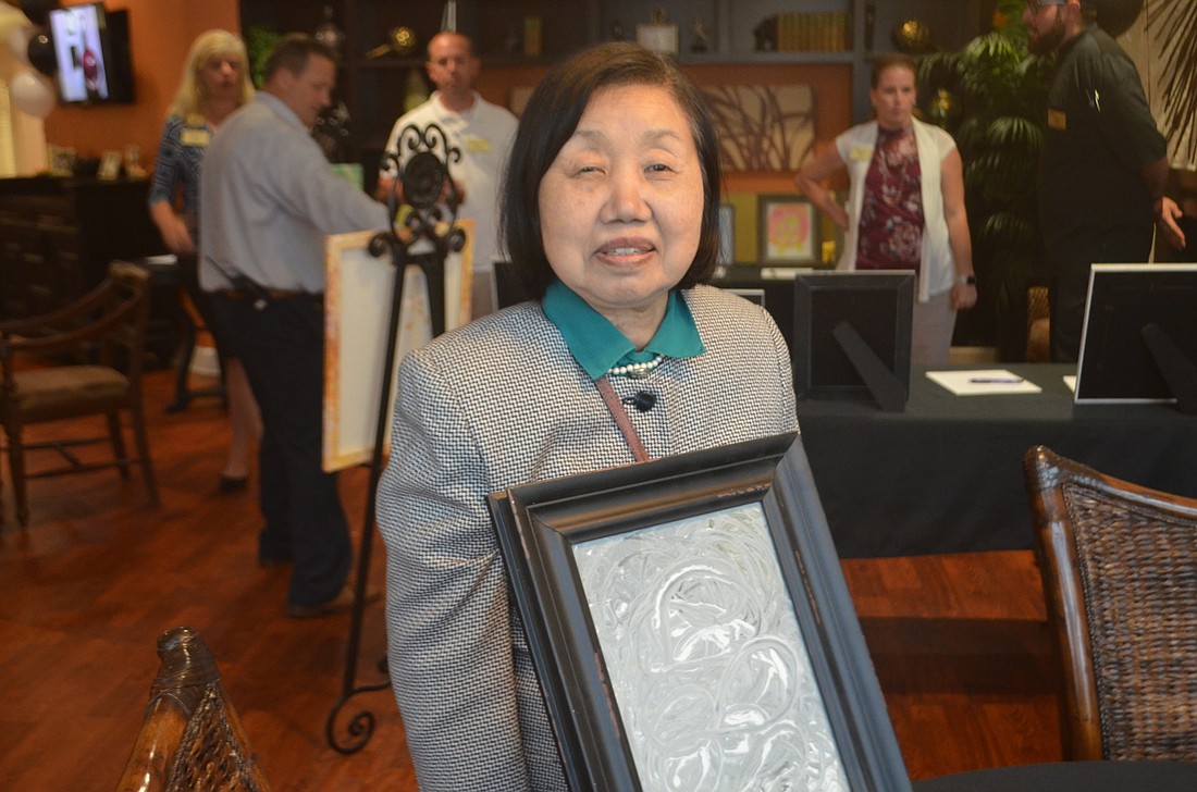 Tomoko Toler, one of the residents at Windsor Reflections, holds up her painting that she made for the auction.