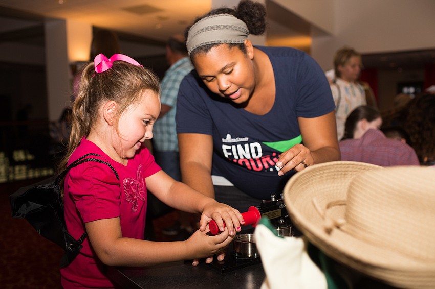 Andrea Dictor helps Alayah Wilson make a button.