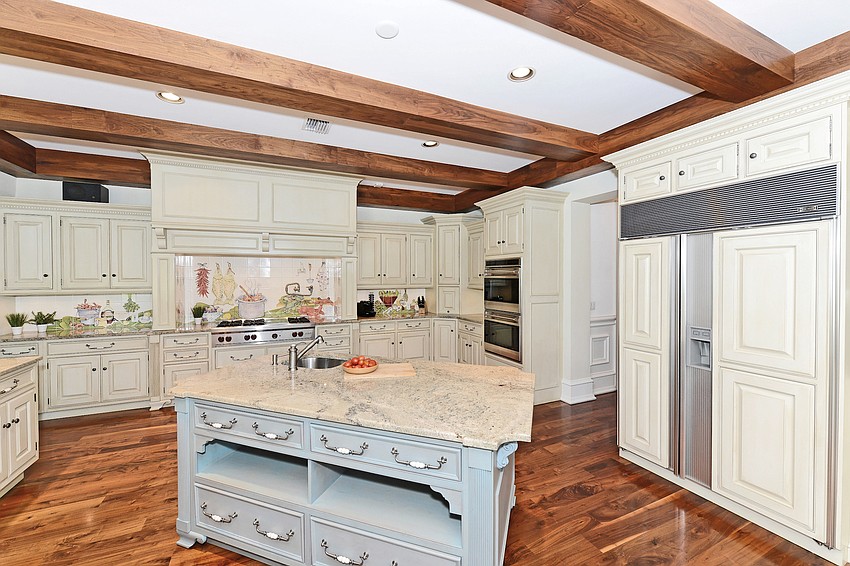 The kitchen features a Wolf six-burner gas cooktop, double convection ovens, warming drawers, Sub-Zero refrigeration, walk-in pantry, large center island and counter seating.