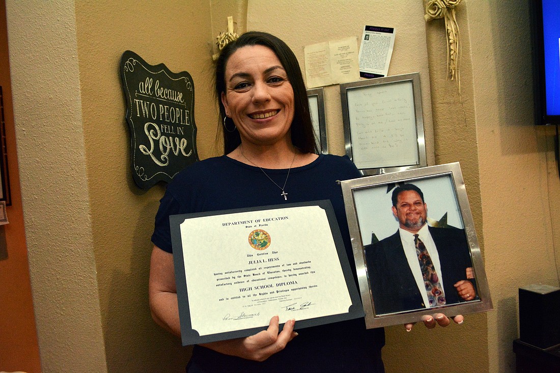 Julie Hess holds her diploma along with a picture of her father, Mark Hollar, who inspired her to advance her education.