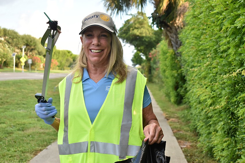 Nancy Rozance holds up some trash she found along the sidewalk.