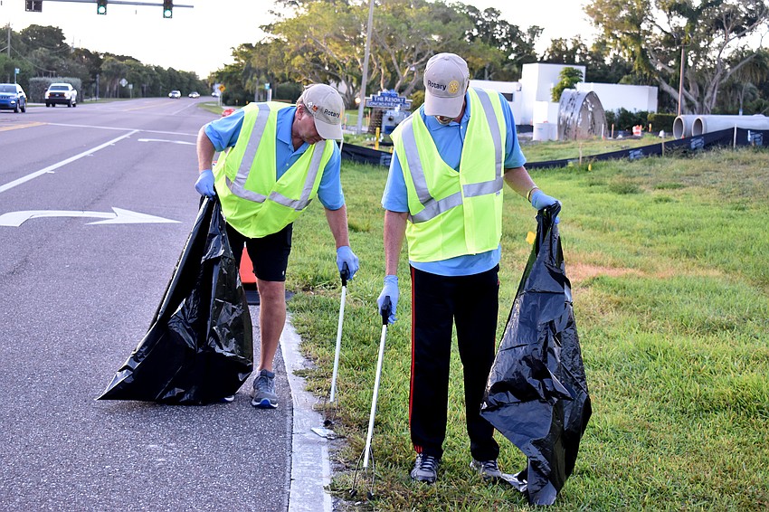 Jack Rozance and Jay Sparr pick up pieces of trash near the road.