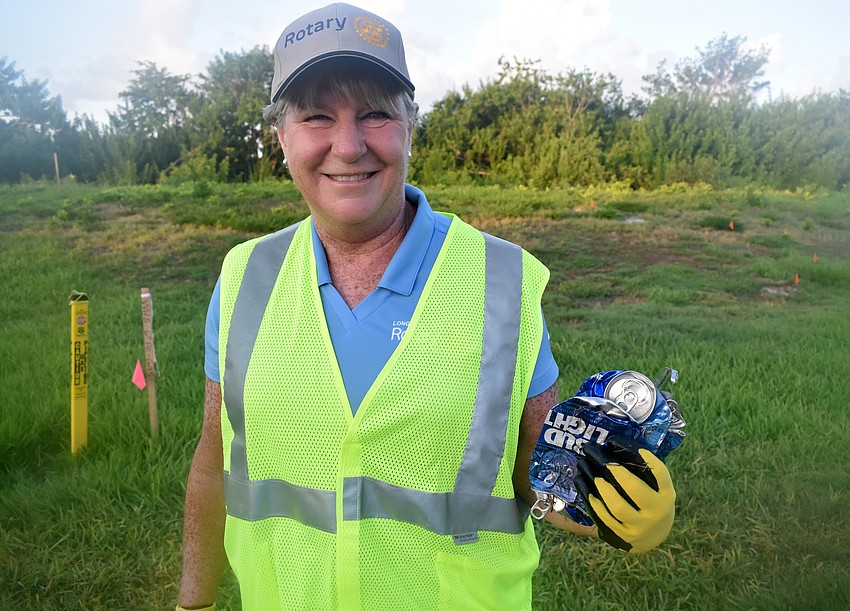 Carol Erker holds up beer cans she found along Gulf of Mexico Drive.