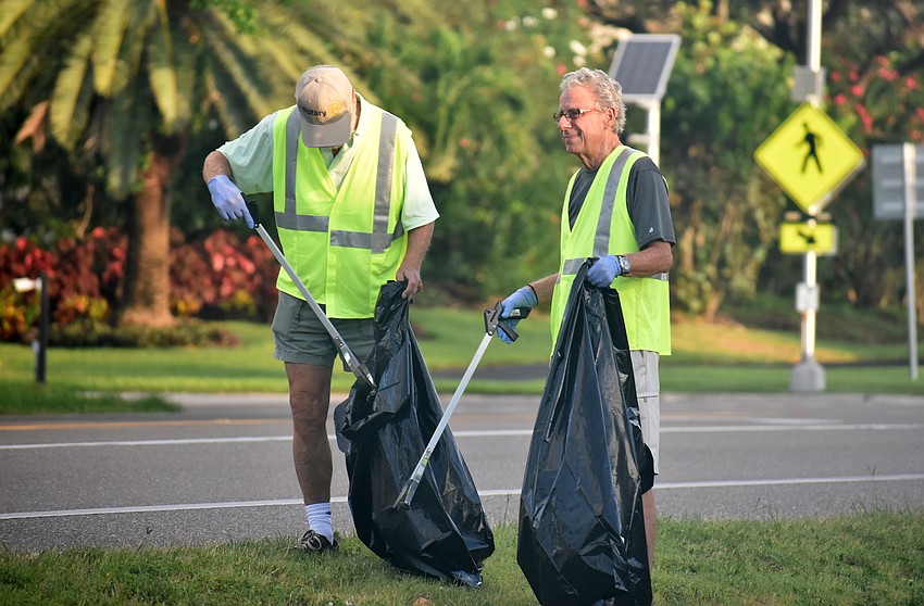 Philippe Koenig and Gene Luca place trash in their bags.