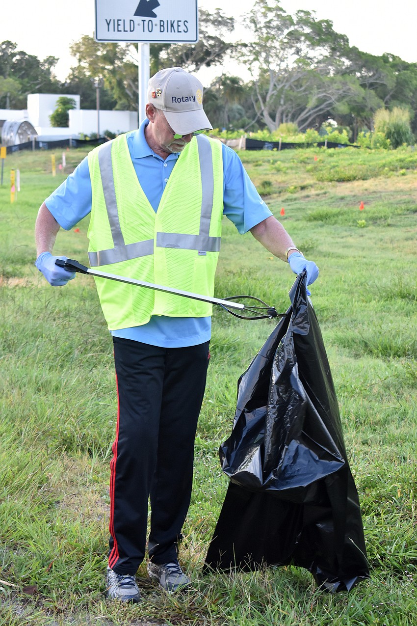 Jay Sparr places trash he found in a garbage bag.