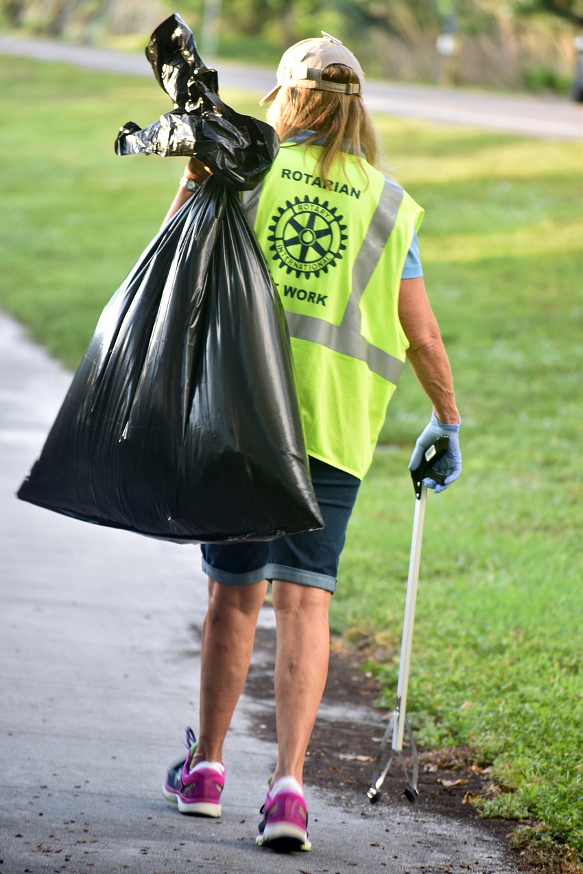 Nancy Rozance carries a garbage bag down Gulf of Mexico Drive.