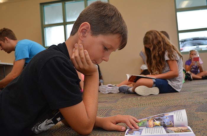 Robert E. Willis Elementary's Noah Ladensack, 8, reads "Superman Alliance of Heroes." He prefers playing sports to reading, but thinks it will help him keep up with school.