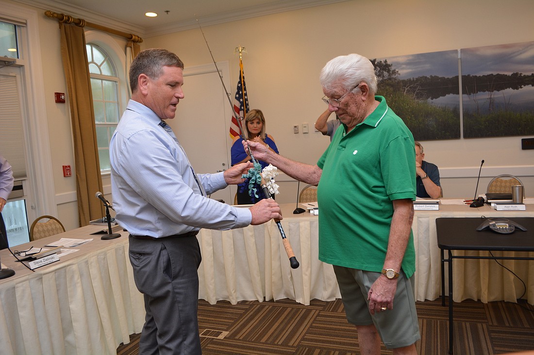 Instead of a plaque, Inter-District Authority Operations Director Paul Chetlain hands Gil Pearce a handcrafted fishing pole made by Chetlain&#39;s stepson Josh Knapek.