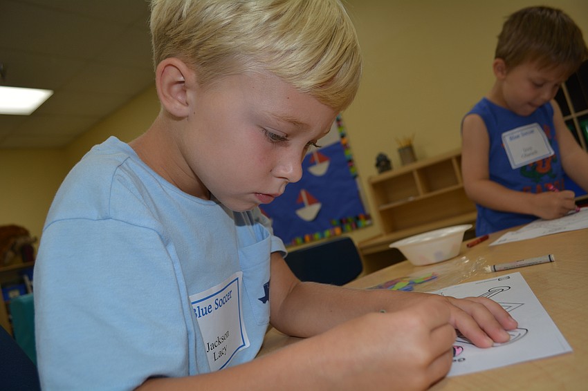Jackson Lacy, 5, colors a baseball maze after creating a mosaic cross.