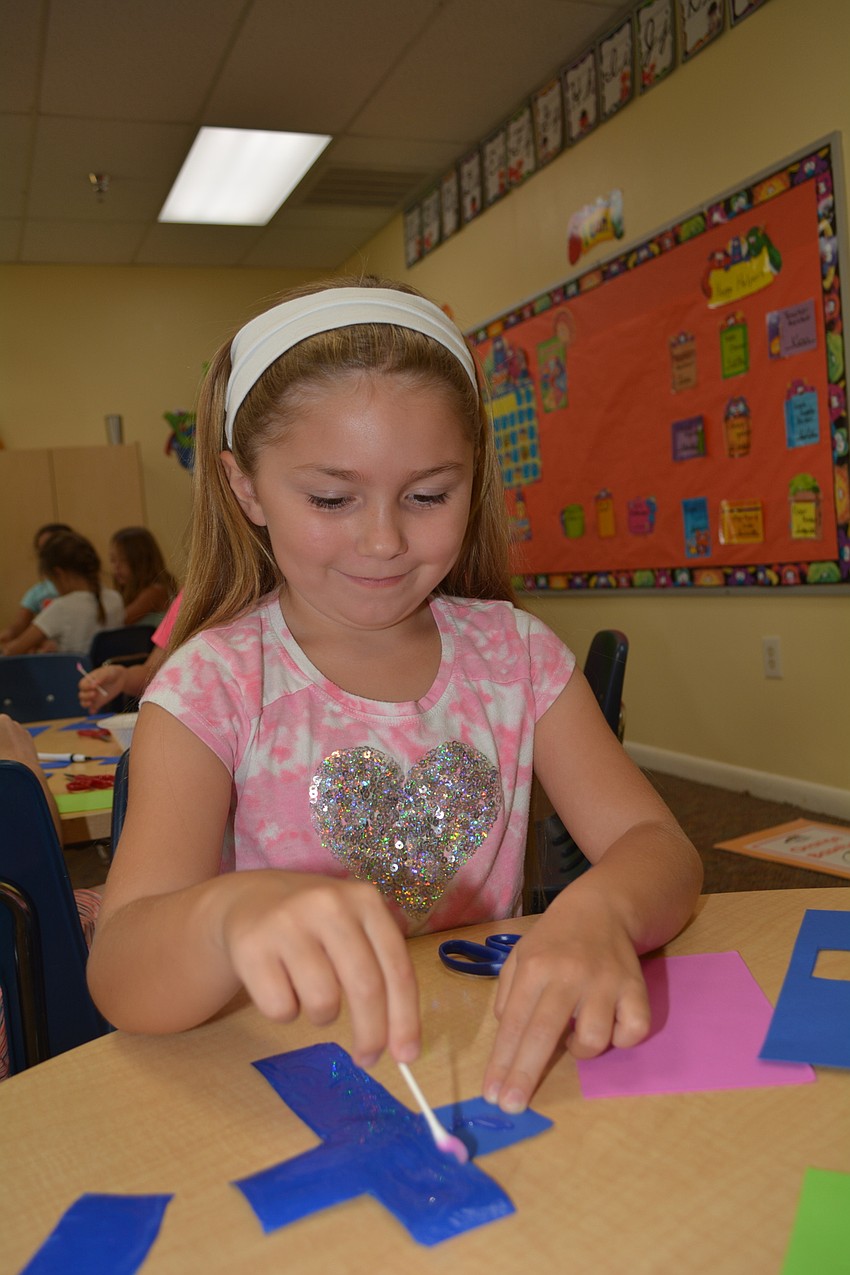 Bashaw Elementary School's Karmyn Ochs, 6, glues together a paper mosaic cross.