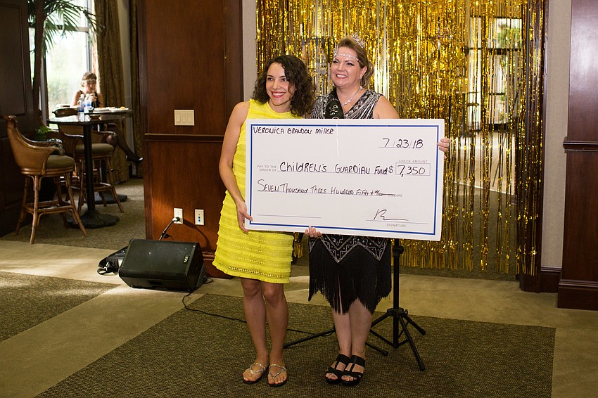Executive Director Svetlana Kaminsky and Veronica Miller hold up the check for the Children's Guardian Fund.