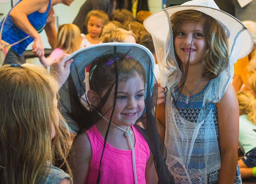 Elliot Hollen and Mia Spirio try on protective hats that are worn by beekeepers.