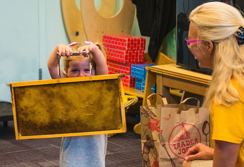 Shayla Fisher holds up a hive frame.