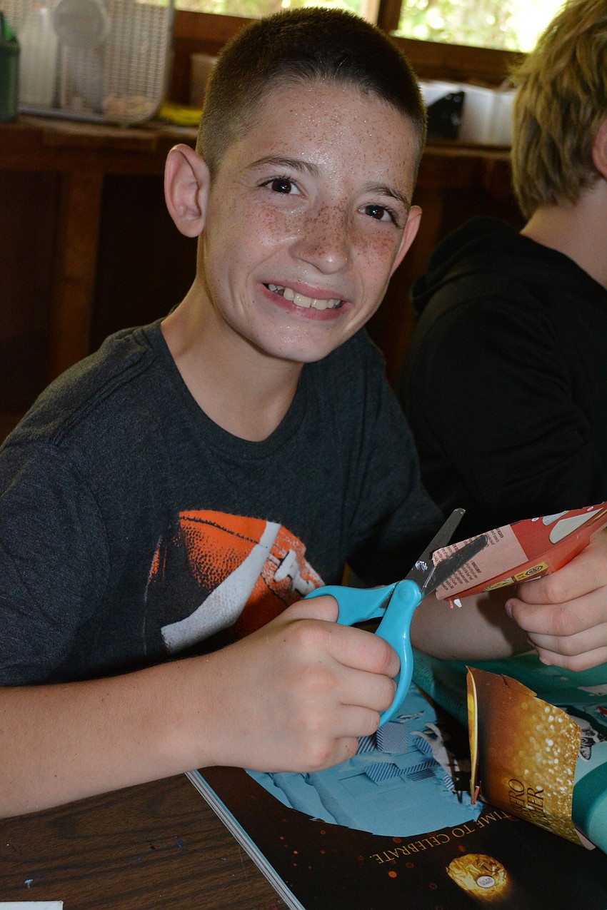 Kye Manning, 11, cuts out a picture of Ferrero Rocher chocolates for a collage used to describe himself.