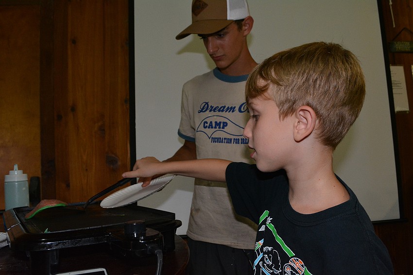 Braden River High School's Beck Stout shows camper Joshua Taber, 8, how to flip a pancake.
