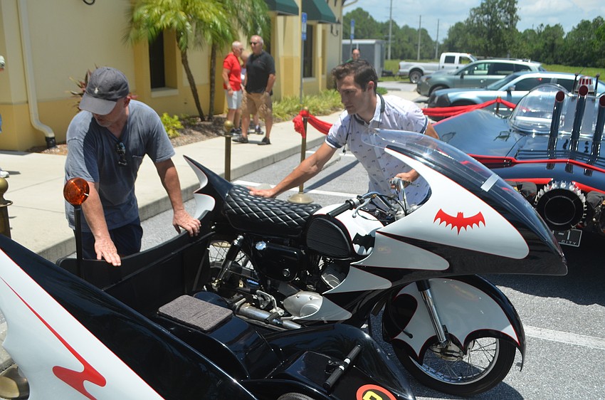 Batmobile coowner John Nock and P.D. Weisman wheel the Batcycle in place next to the Batmobile.