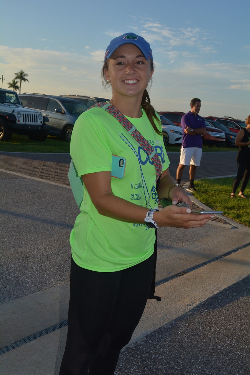 Race organizer Candace Powell, of Lakewood Ranch, plays music for warm-up exercise with her phone.