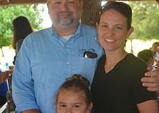 Parrish's Jason Winslow and Christina Winslow grab one of their children, Amelia Winslow, 9, for a picture before she goes out to the playground.