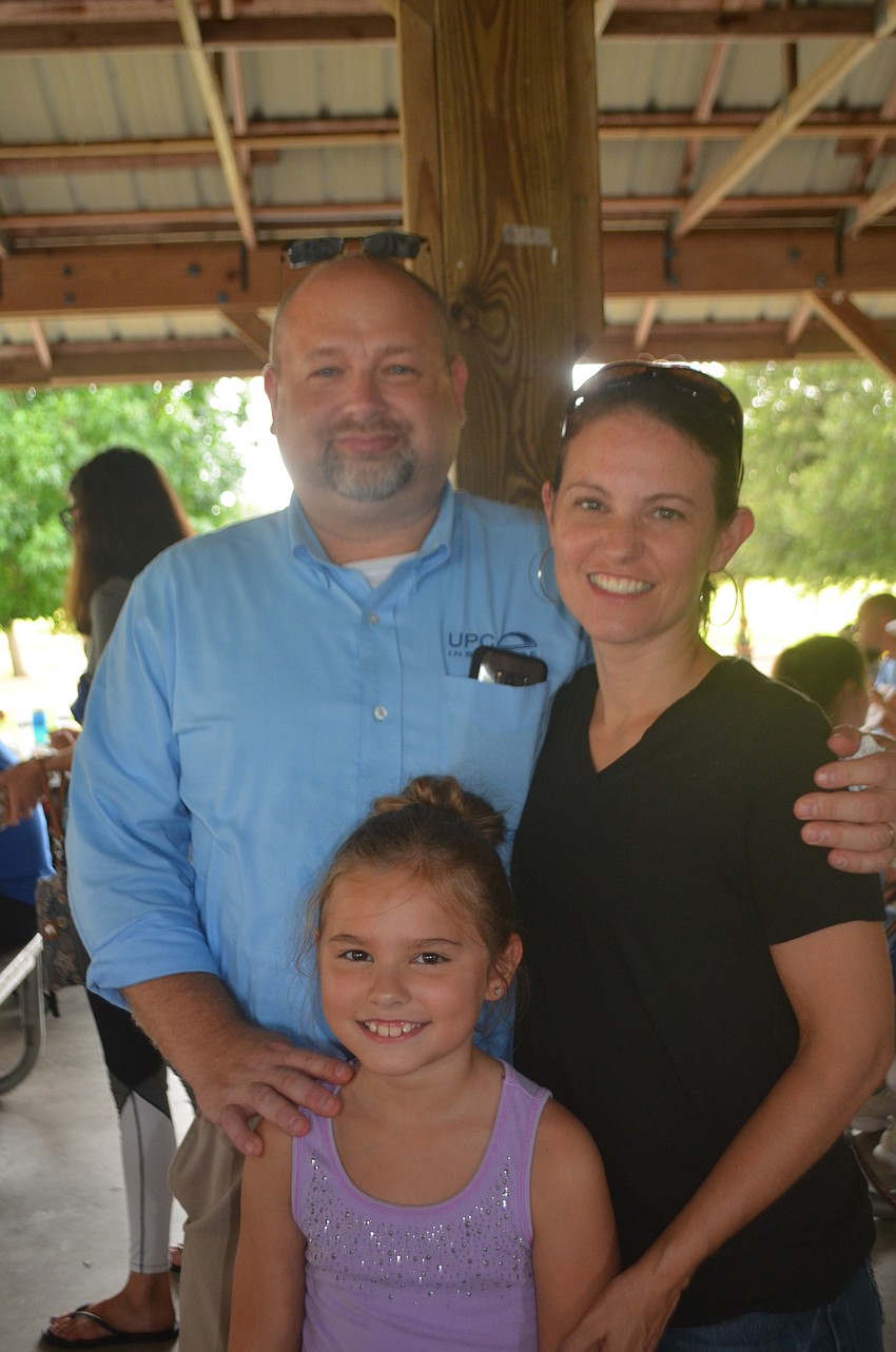 Parrish's Jason Winslow and Christina Winslow grab one of their children, Amelia Winslow, 9, for a picture before she goes out to the playground.