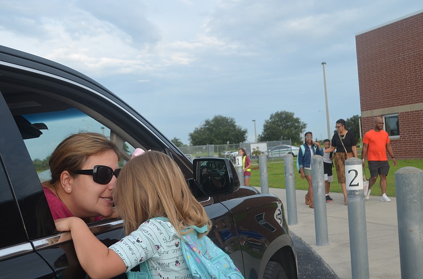 Heidi Johnson gives her daughter Violet Johnson (5) a kiss in the carpool line before her kindergarten teacher brings her back to her classroom.