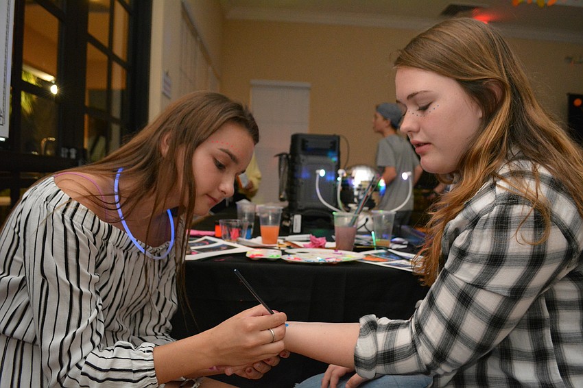 Volunteer Gabi Madrid, of Braden River Middle, and Paige Willemsen, of Lakewood Ranch High, volunteer for the event, but take a quick break for glow paint.