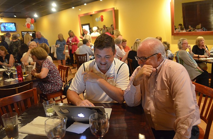 Christian Ziegler, who won the Republican District 2 County Commission primary Tuesday, tracks election results at Gecko's Grill & Pub on Clark Road with a watch party attendee.