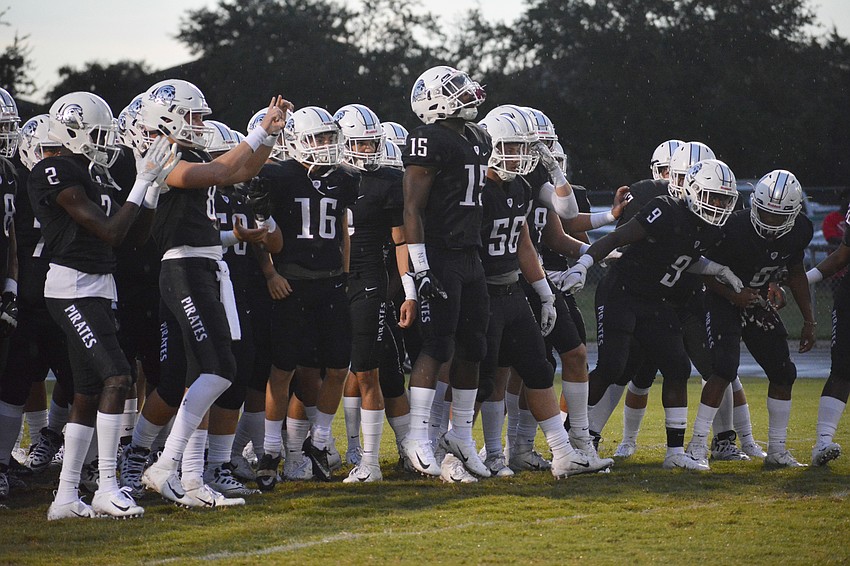 The Pirates, led by the leaping Knowledge McDaniel (15), prepare to run onto the field to start the game.