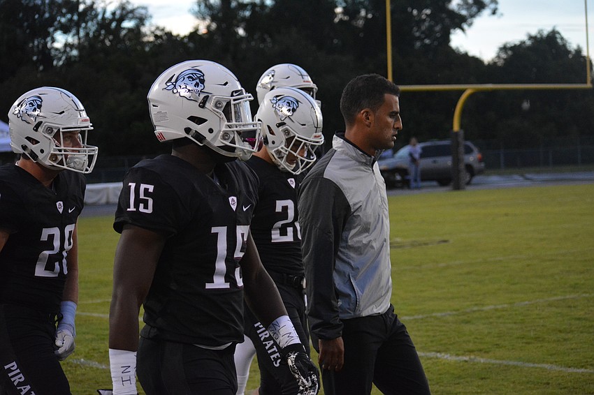 Knowledge McDaniel (15) and head coach Curt Bradley lead the Pirates onto the field for the coin toss.