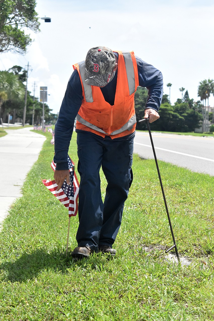 Dale Wyman places an American flag along Gulf of Mexico Drive on Sept. 10.