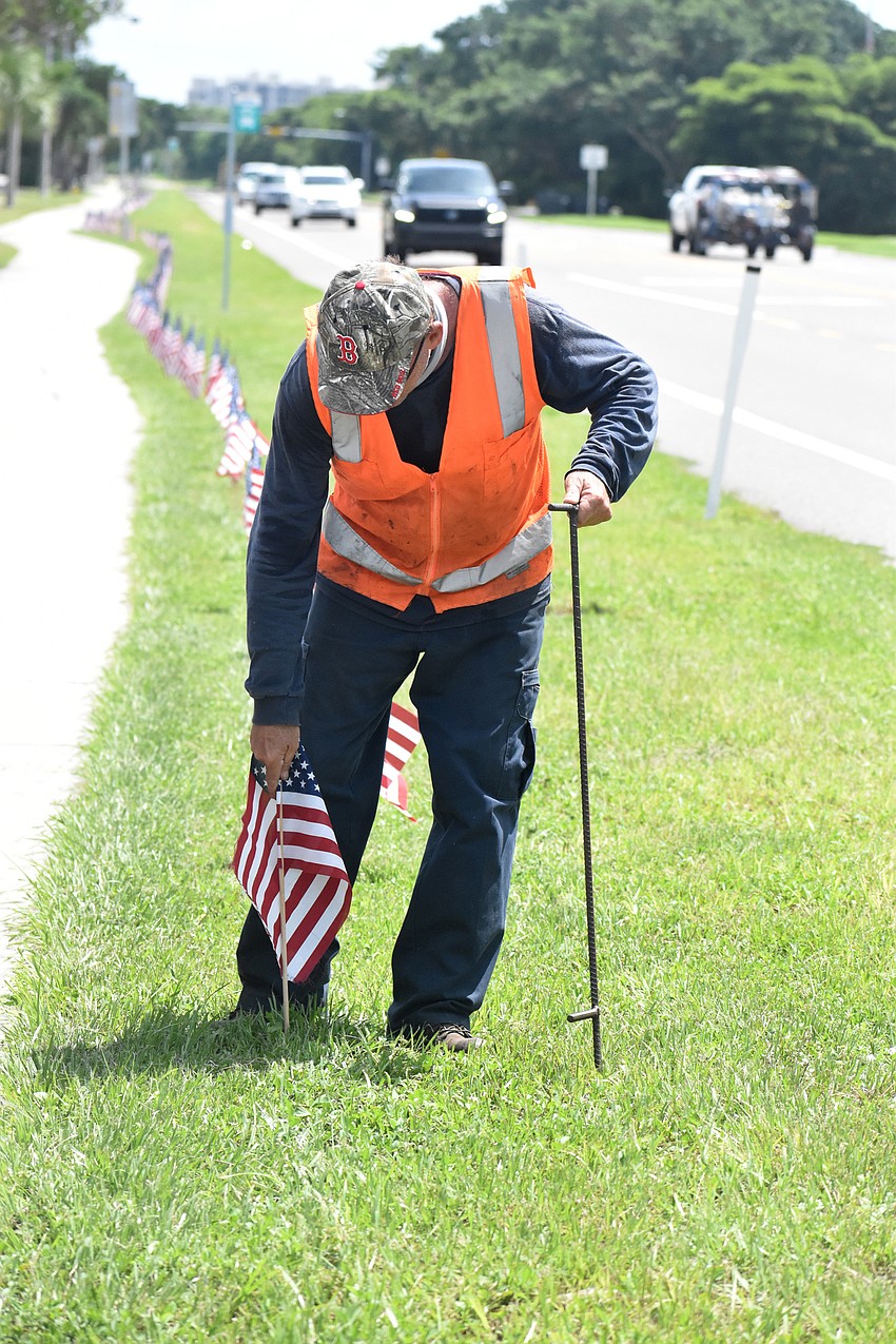 Dale Wyman places an American flag along Gulf of Mexico Drive on Sept. 10.