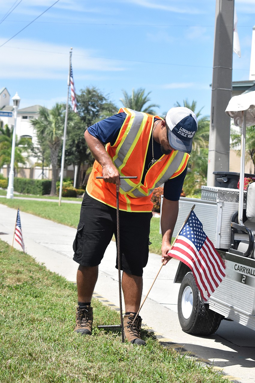 Jeremy Rodriguez walks down Gulf of Mexico Drive as he places a flag about every 20 feet in honor of the 2,977 people who lost their lives on Sept. 11, 2001.