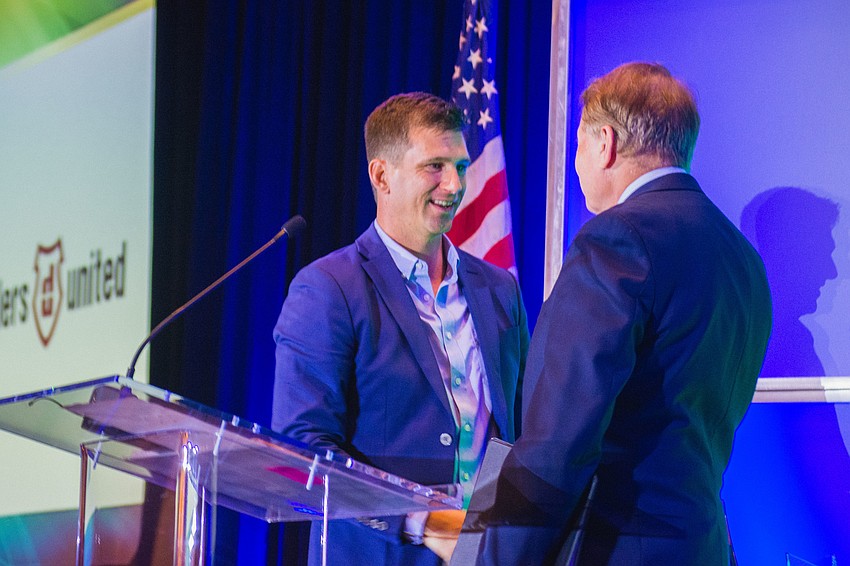 Dealers United CEO Pete Petersen accepts the Ringling College Innovation by Creative Design Award from Ringling College of Art and Design President Larry Thompson.