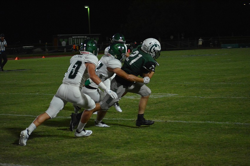 Lakewood Ranch senior Rory Atkins (21) drags a Venice defender for extra yardage.