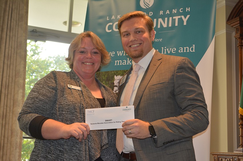 Brandi Ezell of SMART accepts a grant for $3,000 from Lakewood Ranch Community Fund President Garrett Shinn.