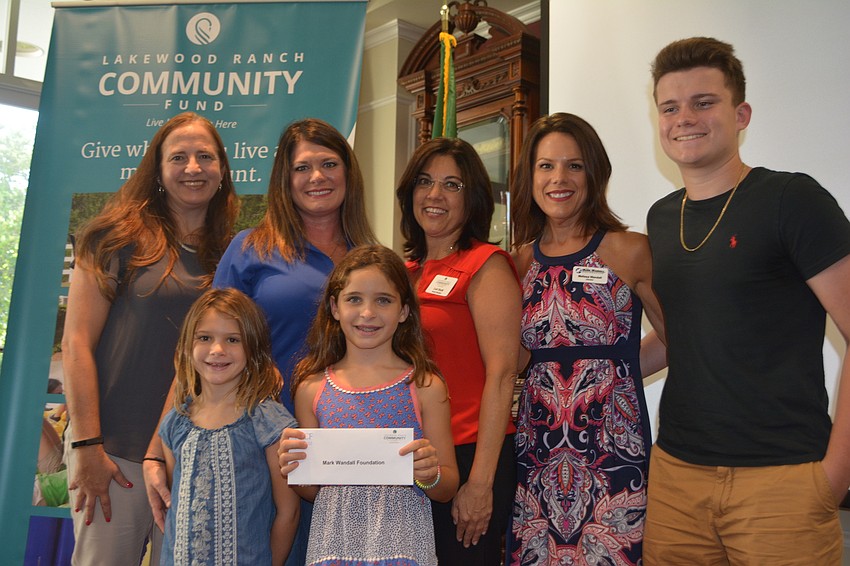 Board member Lori Ruth, middle back, presents a check for $6,400 to (back row) Wendy Orlando, Lindsey Wagner, Melissa Wandall, Brian Tucker and (front row) Sydney Wagner and Hailey Wagner representing the Mark Wandall Foundation.