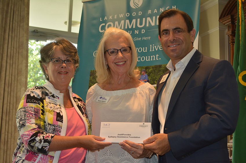 Andria Bilan and Sandra Chapnick of Josh Provides receive a check for  $1,380 from board member David Fink.