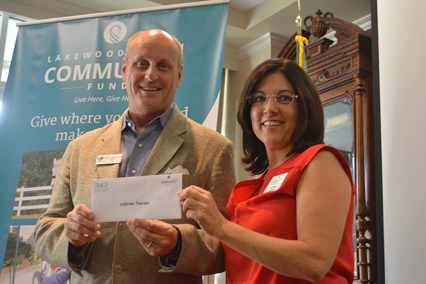 Dana Johnston, the CEO of InStride Therapy, accepts a $3,000 check from board member Lori Ruth.